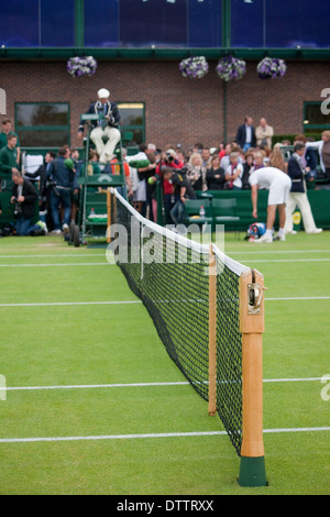 Cour de tennis de Wimbledon ,net en premier plan, avec foule juge-arbitre et joueur de se concentrer en arrière-plan Banque D'Images