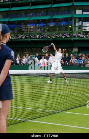 Championnat de Tennis de Wimbledon player exécute avec smash ball girl frais généraux et le bénéfice net en premier plan foule en arrière-plan Banque D'Images