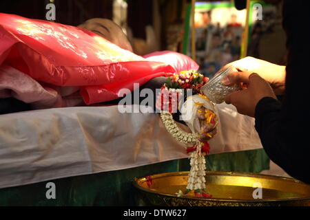 Bangkok, Thaïlande. Feb 24, 2014. Personnes verse de l'eau sur les mains du corps de 6 ans Patcharakorn Yosubon la victime d'une bombe, au cours des derniers rites accomplis dans un temple bouddhiste. Deux jeunes frères et sœurs, fillette de six ans et son Patcharakorn 4 ans Korawit, ainsi qu'une autre femme ont été tués en blessant au moins 22 personnes dans une attaque à la grenade contre des manifestants anti-gouvernement dans le quartier commerçant de Bangkok. Crédit : John Vincent/Alamy Live News Banque D'Images