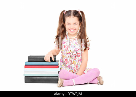 Jolie petite fille assise à côté d'une pile de livres Banque D'Images