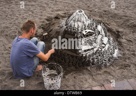 Sculpteur de sable au travail faire une montagne couverte de neige scène à la plage d'El Medano, Tenerife, Canaries, Espagne Banque D'Images