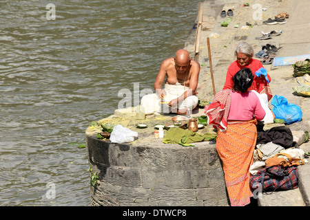 Fidèles hindous avec Bhatta prêtre assis à côté de la rivière Bhagmati dans le temple de Pashupatinath-Kathmandu-Nepal. Banque D'Images