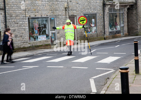 Lollipop man arrêter le trafic à permettre aux gens de traverser la route en toute sécurité, Glastonbury, Somerset, Angleterre Banque D'Images