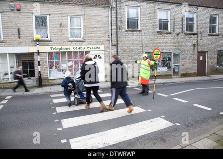 Lollipop man arrêter le trafic à permettre aux gens de traverser la route en toute sécurité, Glastonbury, Somerset, Angleterre Banque D'Images