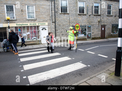 Lollipop man arrêter le trafic à permettre aux gens de traverser la route en toute sécurité, Glastonbury, Somerset, Angleterre Banque D'Images