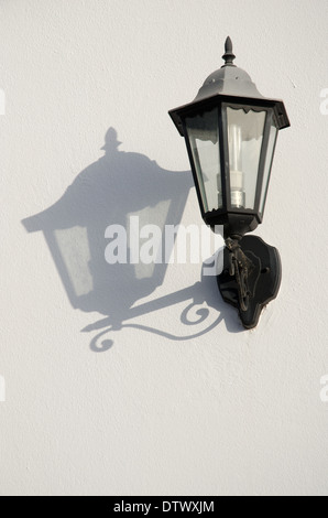 Lampe de mur de fer contre un mur blanc avec une forte ombre Banque D'Images