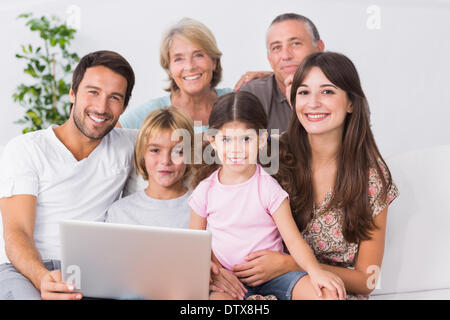 Happy family on couch using laptop Banque D'Images