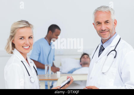 Smiling doctors standing in front of patient Banque D'Images