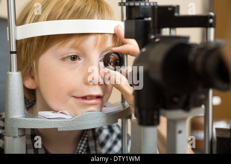 Contrôle de la main de l'opticien Boy's Eye avec lentille Banque D'Images