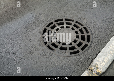 Couvercle de trou d'égout de drainage ronde sur la route asphaltée. Banque D'Images