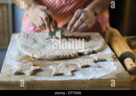 Mixed Race woman cutting cookie dough in kitchen Banque D'Images