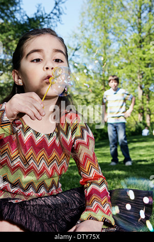 Young Girl blowing bubbles in park Banque D'Images