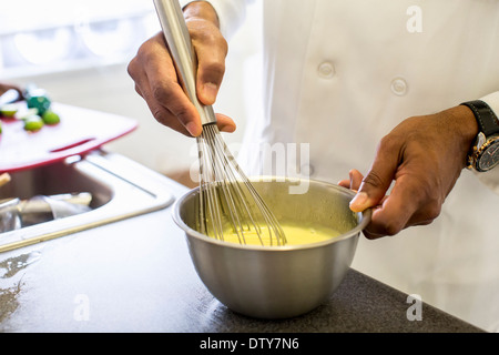 Chef noir en fouettant les oeufs dans restaurant Banque D'Images