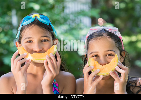 Mixed Race filles jouant avec des cantaloups outdoors Banque D'Images