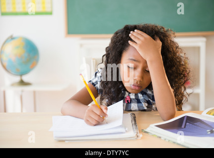 Frustrés mixed race student working in classroom Banque D'Images