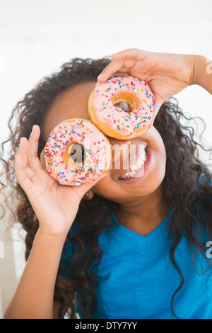 Mixed Race girl holding donuts sur ses yeux Banque D'Images