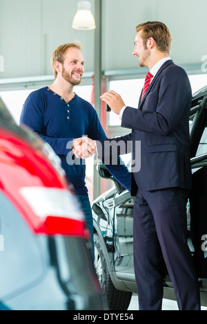 Vendeur ou vendeur de voiture et client en concession, ils se serrer la main, les mains sur les clés de voiture Banque D'Images