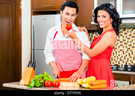 Asian couple cooking et couper des légumes dans la cuisine domestique, de boire du vin rouge Banque D'Images