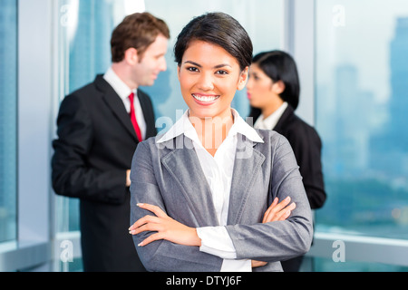 L'équipe entreprises asiatiques dans office, la femme à l'avant avec skyline Banque D'Images