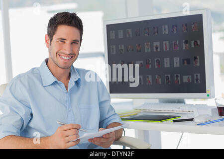 Handsome photo editor holding documents Banque D'Images