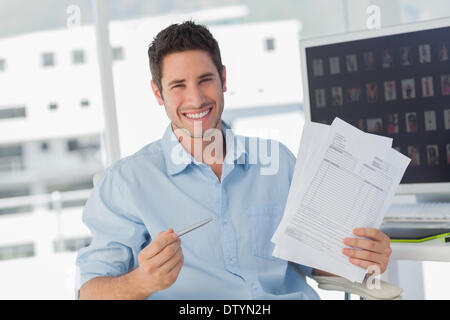 Cheerful photo editor pointing at documents Banque D'Images