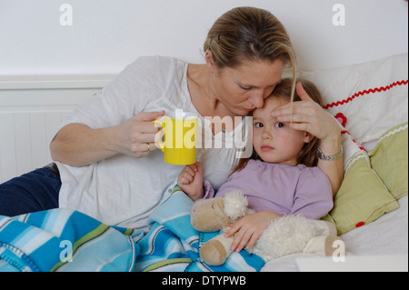 Mère en prenant soin de sa fille malade, distribution de thé chaud, girl Lying in Bed Banque D'Images