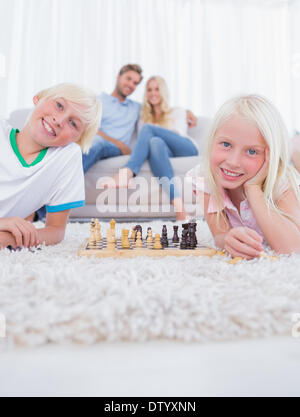 Les enfants se trouvant sur un tapis en jouant aux échecs Banque D'Images