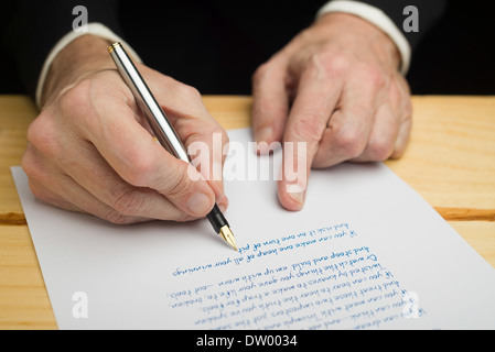 Un homme d'écrire avec un stylo sur un papier blanc fixé sur un pont boisé Banque D'Images