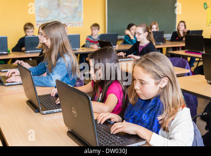 Des élèves du premier cycle du secondaire (environ 12 ans) travailler avec leur ordinateur portable dans leur classe. Banque D'Images