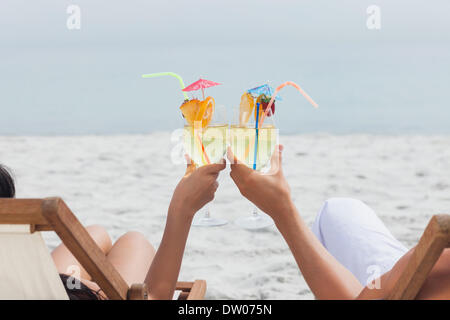 Couple clinking glasses of cocktail on beach Banque D'Images