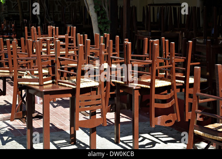 Restaurant fermé avec des chaises en bois brun fixé à l'envers sur les tables à jour d'été ensoleillé. Banque D'Images