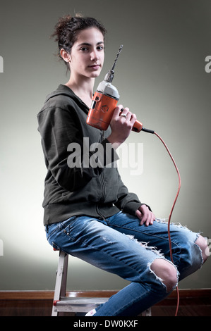 Jeune femme tenant un exercice tout en étant assis sur l'échelle Banque D'Images