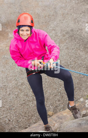 Happy girl ascending rock face Banque D'Images