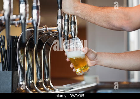 Barmans arms pulling a pint of beer Banque D'Images