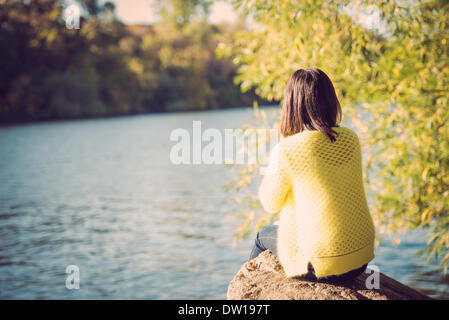 Femme assise à côté d'une rivière Banque D'Images