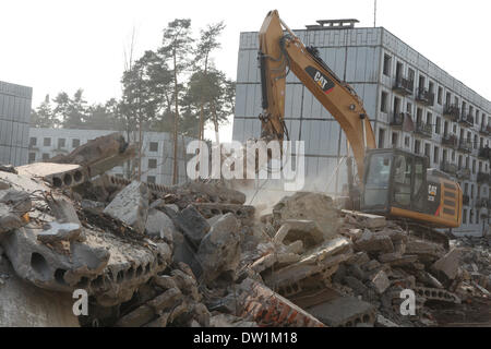 Milovice, République tchèque. 25 février 2014. Une Pelle de démolition des bâtiments d'habitation abandonnés détruit qui ont été utilisés pour les officiers de l'armée soviétique dans le domaine de la base militaire soviétique à Milovice, situé à environ 40 km de Prague, République tchèque. Ruines de l'ancienne base militaire soviétique en Milovice doivent être démolis au cours des quelques prochains mois pour faire place à de nouveaux bâtiments. La base a été abandonnée depuis plus de vingt ans, depuis le départ des troupes soviétiques de la Tchécoslovaquie en 1991. Maintenant la base militaire abandonnée survit pour le dernier jours. Banque D'Images