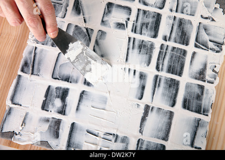 S'applique au travailleur de coulis carreaux gris Banque D'Images