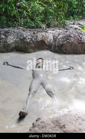 L'homme de prendre un bain de boue au volcan sur l'île de Tiga, Bornéo, Malaisie Banque D'Images