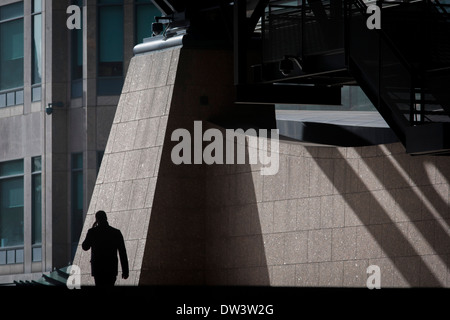 Silhouette unique de l'homme marchant à travers la Broadgate bureaux d'entreprise le développement dans la ville de Londres. Banque D'Images