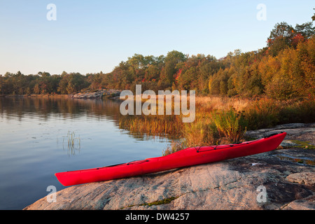 Un kayak repose sur un rivage rocailleux au lever du soleil dans le Massasauga Parc Provincial de l'Ontario, Canada. Banque D'Images