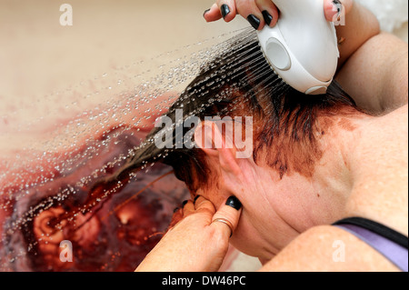 Rinçage de la femme plus d'une teinture à l'aide d'une tête de douche baignoire Banque D'Images