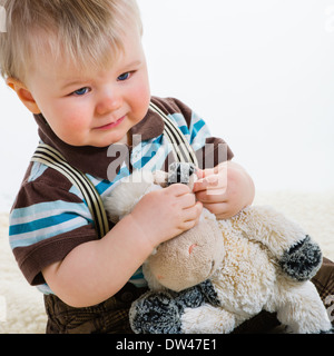 Bébé garçon, 16 mois portant chemise rayée et bretelles, fond blanc Banque D'Images