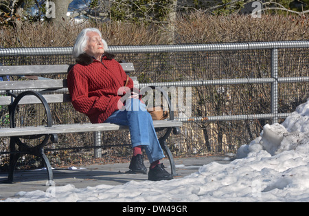 Peu de temps après une tempête de neige, une femme de soleil par une froide après-midi d'hiver sur la promenade à Coney Island, Brooklyn, New York. Banque D'Images