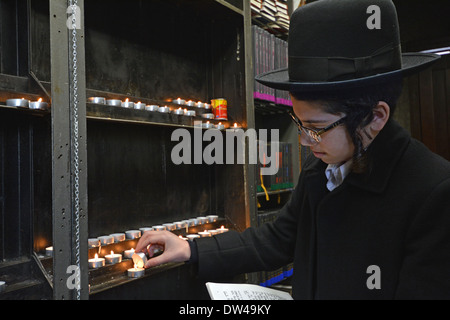 Garçon juif religieux allume une bougie avant de visiter la tombe du Rav Loubavitch à Cambria Heights, dans le Queens, New York Banque D'Images