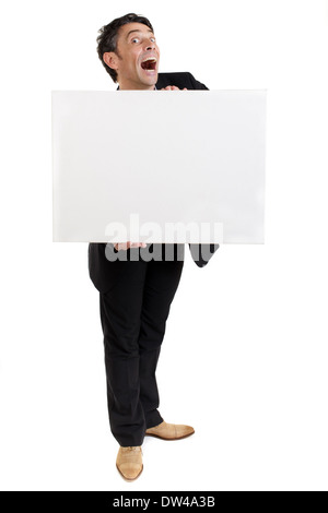 Businessman holding a blank white card ou signer en face de sa poitrine avec une exagération de la regarder bouche bée d'étonnement Banque D'Images