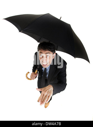 High angle humoristique full length portrait of a businessman s'abritant sous son parapluie sur le contrôle de la pluie Banque D'Images