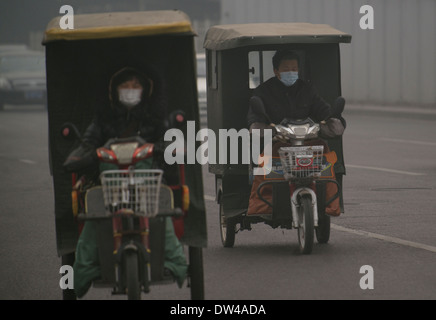 Deux cyclistes portent des masques tôt le matin à Beijing le 26 février 2014 Banque D'Images