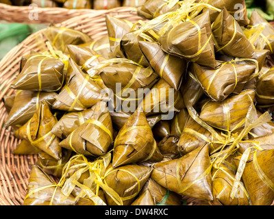 Dessert asiatique traditionnel fabriqué à partir de pâte de riz et de noix de coco sucrée enveloppés dans des feuilles de banane Banque D'Images