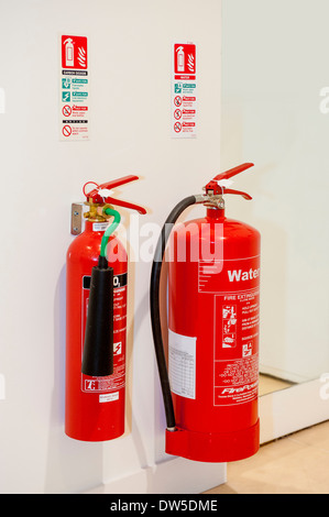 Le dioxyde de carbone et les extincteurs d'eau montés sur un mur de bureau, ainsi que des instructions sur leur utilisation.UK Banque D'Images