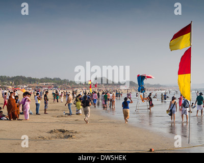 L'Inde, Goa, Baga, touristes indiens sur la plage, entre les drapeaux de baignade sécuritaire de sauveteur Banque D'Images